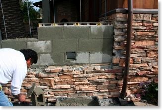 The stone veneer of the house will blend into the barbecue island