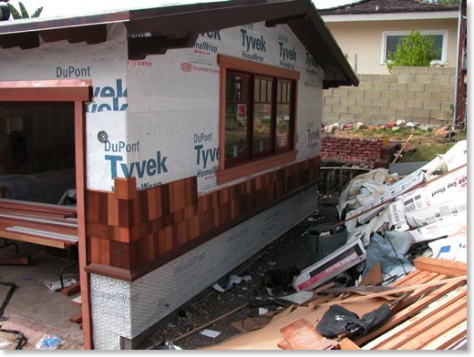 Tyvek, shingles, and trim are installed on the house exterior.